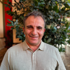 Zia Shlaimoun on vacation in Las Vegas, wearing a beige polo shirt, smiles outdoors